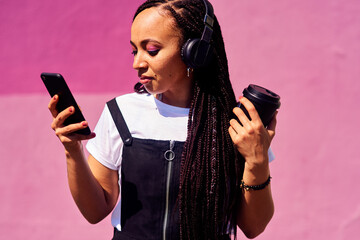Woman, headphones and outdoor on phone or coffee, streaming sound and subscription by pink...