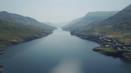 An aerial view of a serene river flowing between lush green hills with a rural settlement alongside.