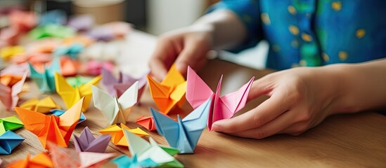 A man's hand engaged in origami while browsing a smartphone screen, against a background with copy space image.