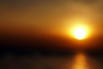Blurred Tranquil scene of big red sun and yellow sky sunset over the sea at pattaya Thailand.