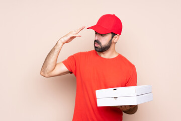 Young man holding a pizza over isolated background with tired and sick expression