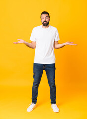 Full-length shot of man with beard over isolated yellow background having doubts while raising hands