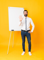 Full-length shot of businessman giving a presentation on white board over isolated yellow...