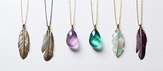 Top view of a handmade bijouterie with turquoise and violet hues adorned with gems, tassels, and feathers resting on a white background with abundant copy space image.