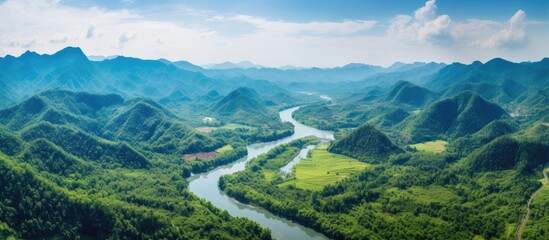 Naklejka premium Aerial drone shot of a picturesque river in the lush green tropical forest of Southeast Asia with mountains in the backdrop, perfect for copy space image.