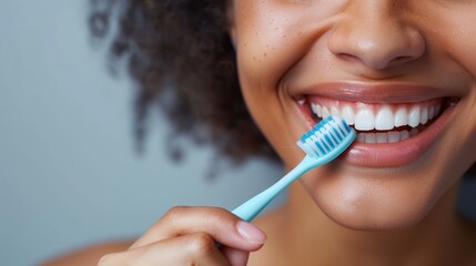 Close-up photography of a woman’s hand holding a toothbrush with bright white teeth perfect for dental and health themes