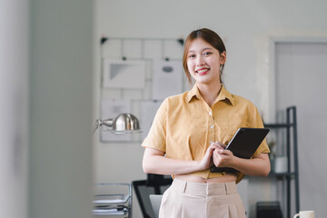 Confident young professional asian woman using tablet in modern office.