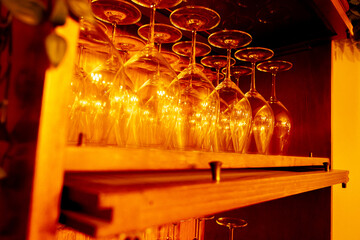 A wooden shelf with many wine glasses on it