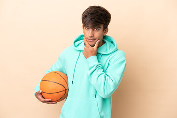 Handsome young basketball player man isolated on ocher background thinking