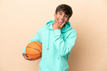 Handsome young basketball player man isolated on ocher background happy and smiling