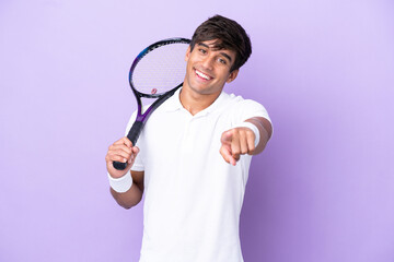 Handsome young tennis player man isolated on ocher background pointing front with happy expression