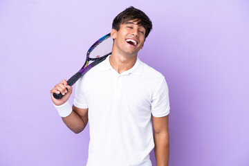 Handsome young tennis player man isolated on ocher background laughing