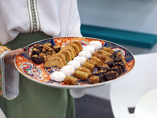 Assorted Arabic sweet pastries on a tray to taste carried by a person