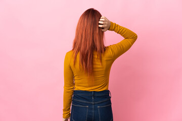 Teenager Russian girl isolated on pink background in back position and thinking