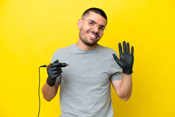 Tattoo artist caucasian man isolated on yellow background saluting with hand with happy expression
