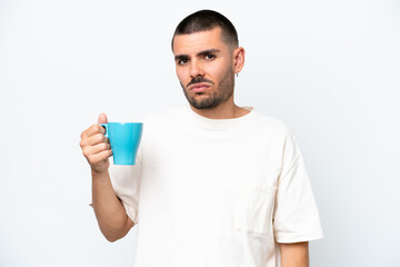 Young caucasian man holding cup of coffee isolated white background with sad expression