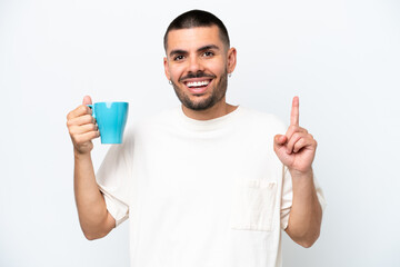 Young caucasian man holding cup of coffee isolated white background pointing up a great idea