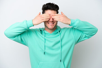 Young caucasian man isolated on white background covering eyes by hands and smiling
