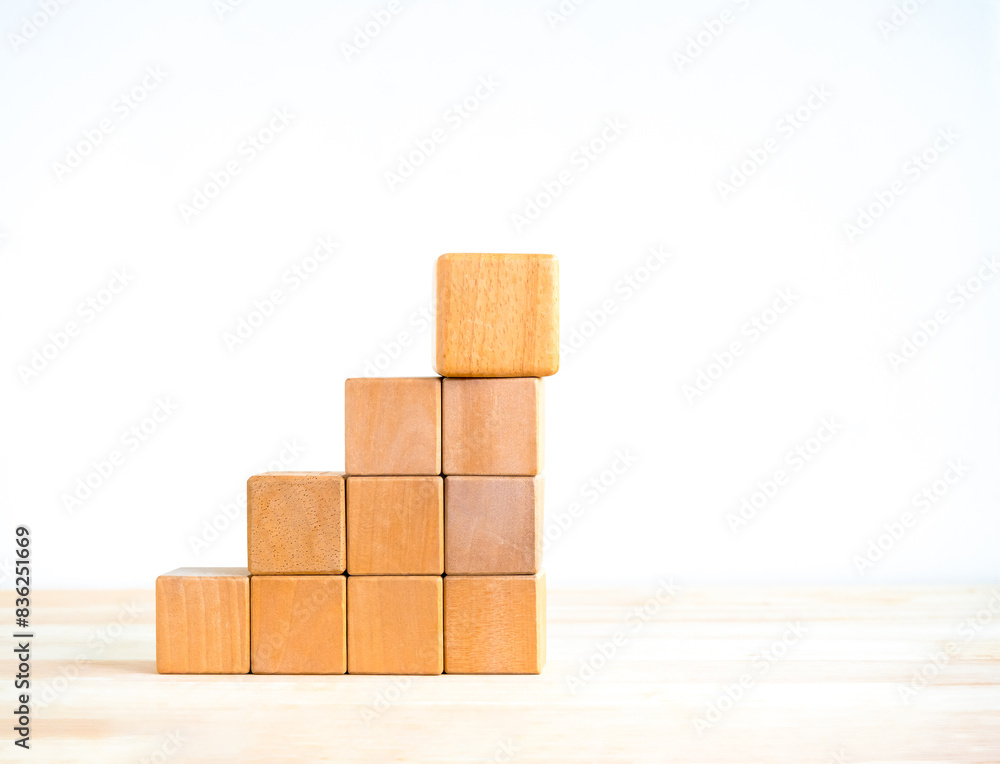 Poster empty blank wooden cube blocks as growth graph steps with a big one on top, isolated on wood desk on