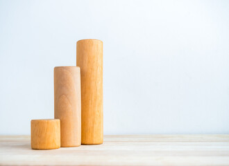 Three size of round wooden sticks as a business chart steps isolated on wood desk on white background with copy space. Business growth graph process, goal, success, and economic improvement concepts.