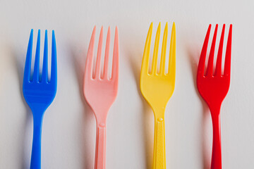 flat lay of 4 four Multicolored forks arranaged side by side over white background