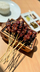 Homemade lamb or mutton satay marinated with spice and sweet soy sauce, coriander goat satay, served with chilli, soy sauce and tomato. Indonesian traditional satay