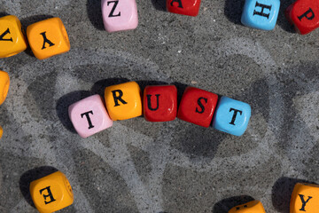 Colourful wooden blocks spelling trust on a stone with graffiti concept of trusting



