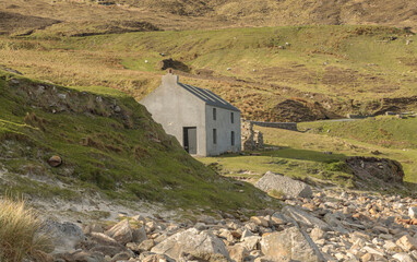 Grey building on a shoreline of rocks and stones