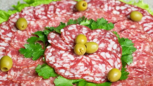Beautiful serving of salami with garnished with olives and herbs, cold cuts