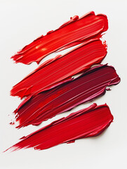 Smeared swatches of red lipstick in a set of several shades on a light background