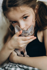 A child and her new pet. A happy 6-year-old girl who was presented with a small hairless sphynx kitten