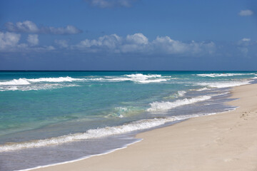 Empty sea beach with white sand, view to azure waves and blue sky with cloud. Caribbean coast, background for holidays on a paradise nature