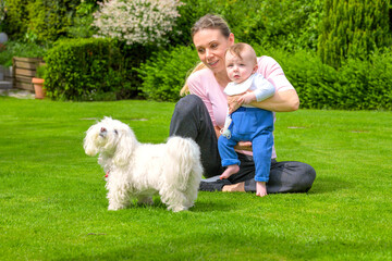 Mother and Baby Enjoying the Garden with a Fluffy Dog