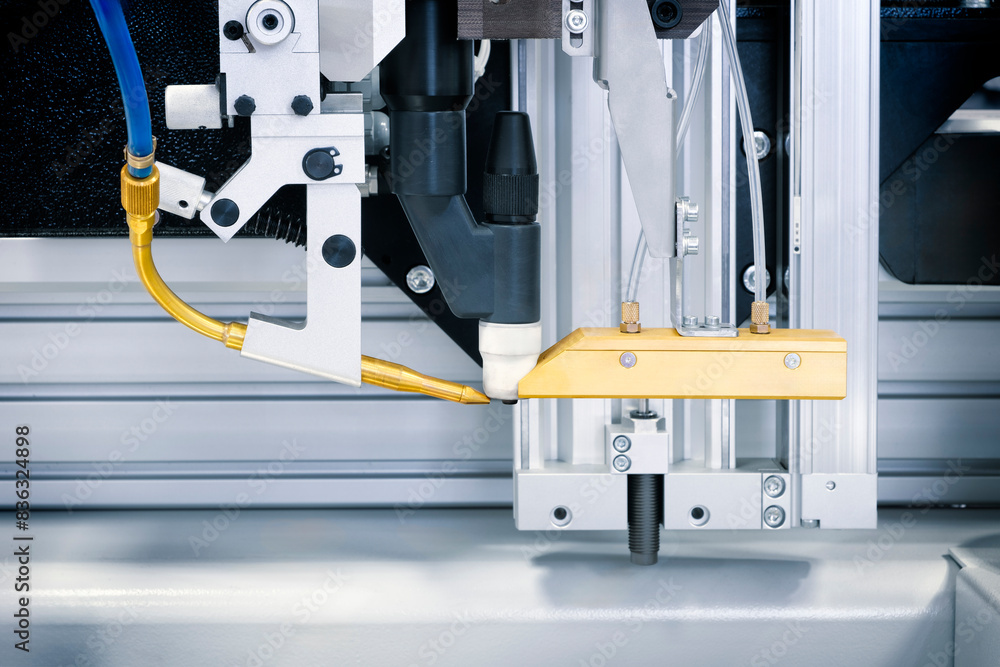 Poster a machine with a yellow hose attached to it. the machine is in a factory setting. the yellow hose is