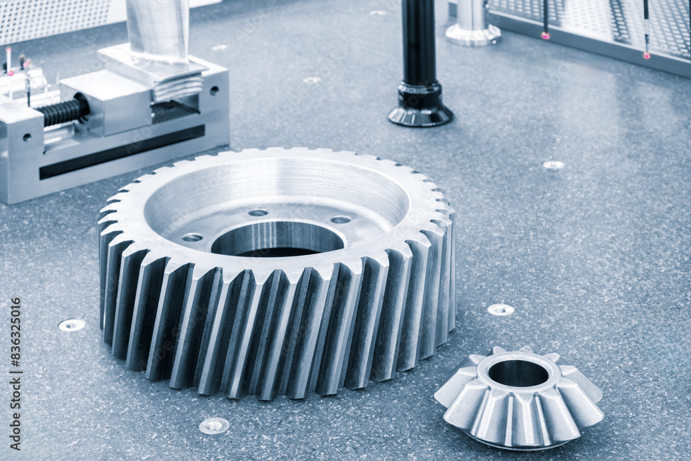 Poster The gear lies on the table next to another gear on the cmm measuring table. The two gears are made of metal and have different sizes. Precision and engineering concept