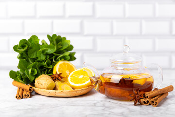 Fragrant hot tea with cinnamon stick and anise on a textured wooden background. A teapot brewing hot tea with honey, lemon, mint and apples. Spicy tea with spices. Immunity tea. Health concept.