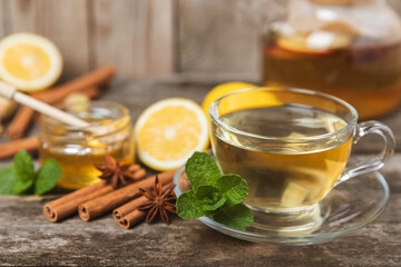 Fragrant hot tea with cinnamon stick and anise on a textured wooden background. A cup of hot tea with honey, lemon, mint and apples. Spicy tea with spices. Immunity tea. Health concept.Copy space.