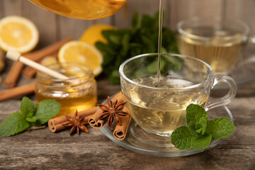 Fragrant hot tea with cinnamon stick and anise on a textured wooden background. A cup of hot tea with honey, lemon, mint and apples. Spicy tea with spices. Immunity tea. Health concept.Copy space.