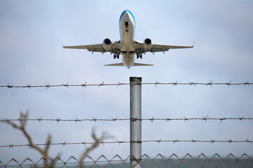 Passenger plane flying behind stainless steel fencing wire. Aviation idea concept. Deported. International travel. Airplane taking off.