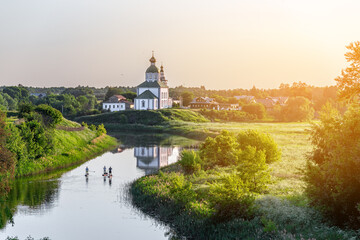Summer landscape in Suzdal. Church of Elijah the Prophet on the bank of the river Kamenka. Tourists...