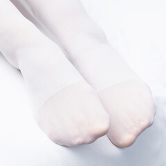 Medical compression stockings for varicose veins and venous therapy. Compression knitwear. A woman is lying at home or in a hospital on a bed with a white sheet.