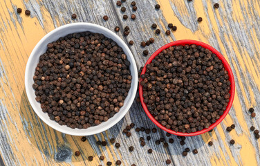 bowls filled with black peppers (Piper nigrum). Native to Malabar coast of India, it is widely used in culinary as spice and seasoning around the world.