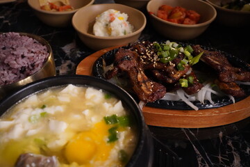 Korean Soft Tofu Soup (soondubu) with a plate of grilled short ribs and small side dishes (ban chan) 