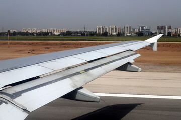 The wing of a jet plane and the scenery on the ground are visible through the porthole.