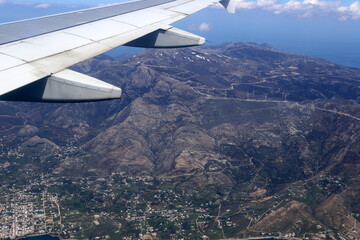 The wing of a jet plane and the scenery on the ground are visible through the porthole.