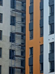 The façade of an apartment building is being insulated at a construction site