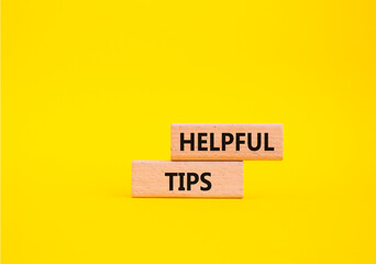 Helpful tips symbol. Wooden blocks with words Helpful tips. Beautiful yellow background. Business and Helpful tips concept. Copy space.