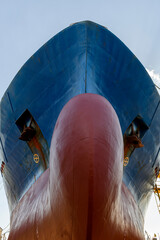 Cargo vessel in dry dock on ship repairing yard. Bulbous bow.