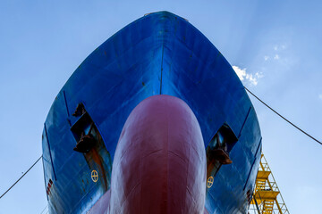 Cargo vessel in dry dock on ship repairing yard. Bulbous bow.