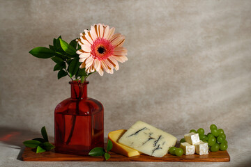 Concept for the Jewish holiday Shavuot gerbera flower, pieces of cheese on a white wooden board.